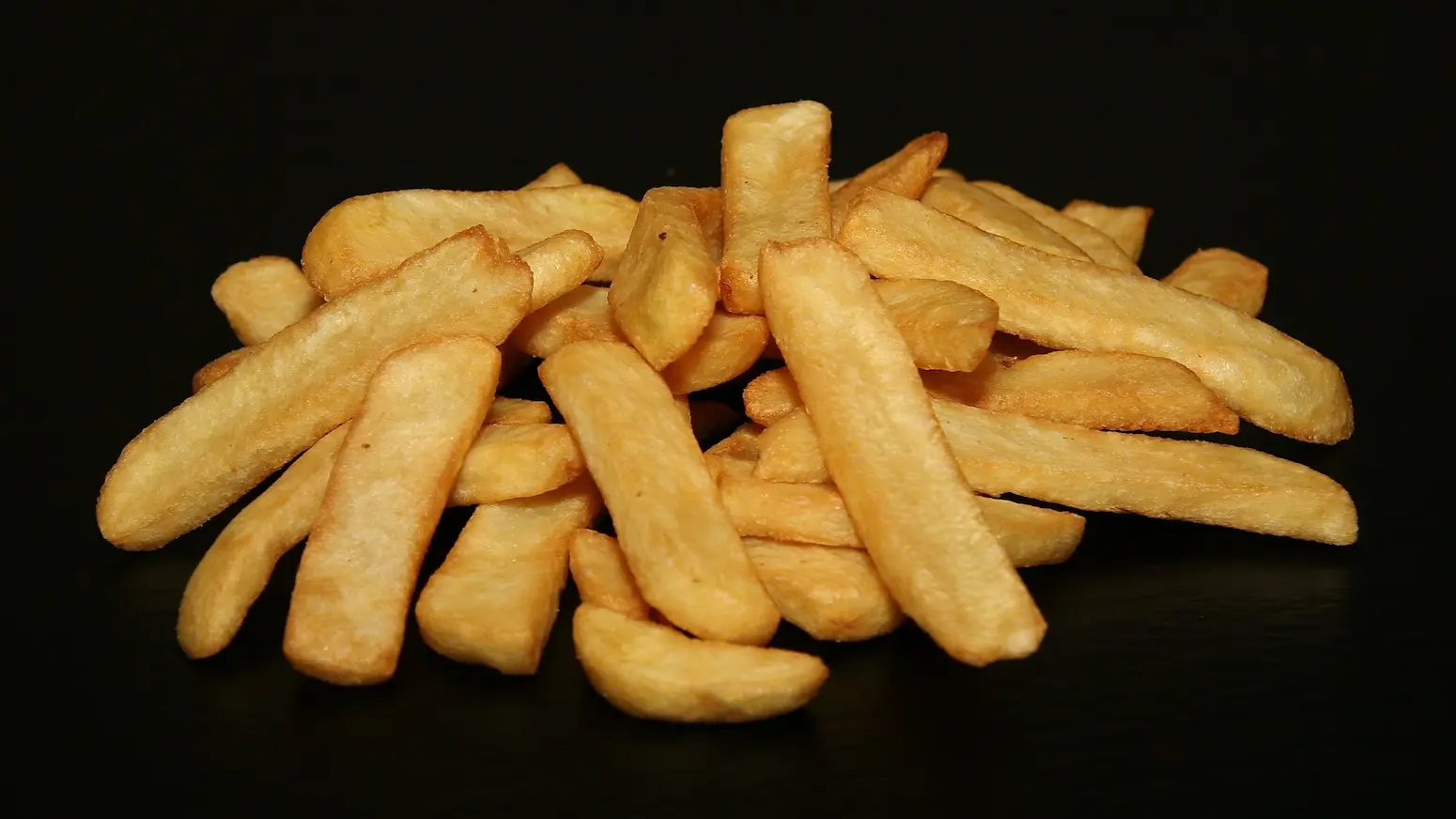 Golden crispy potato wedges closeup with black background